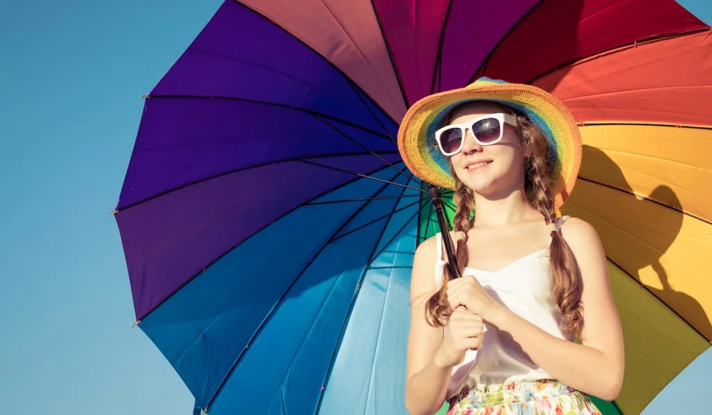 teen girl holding a beach umbrella